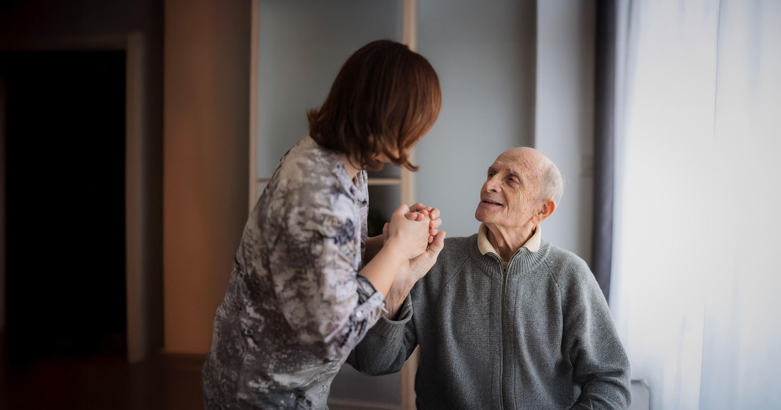 An adult female communicating with an elderly man with dementia.